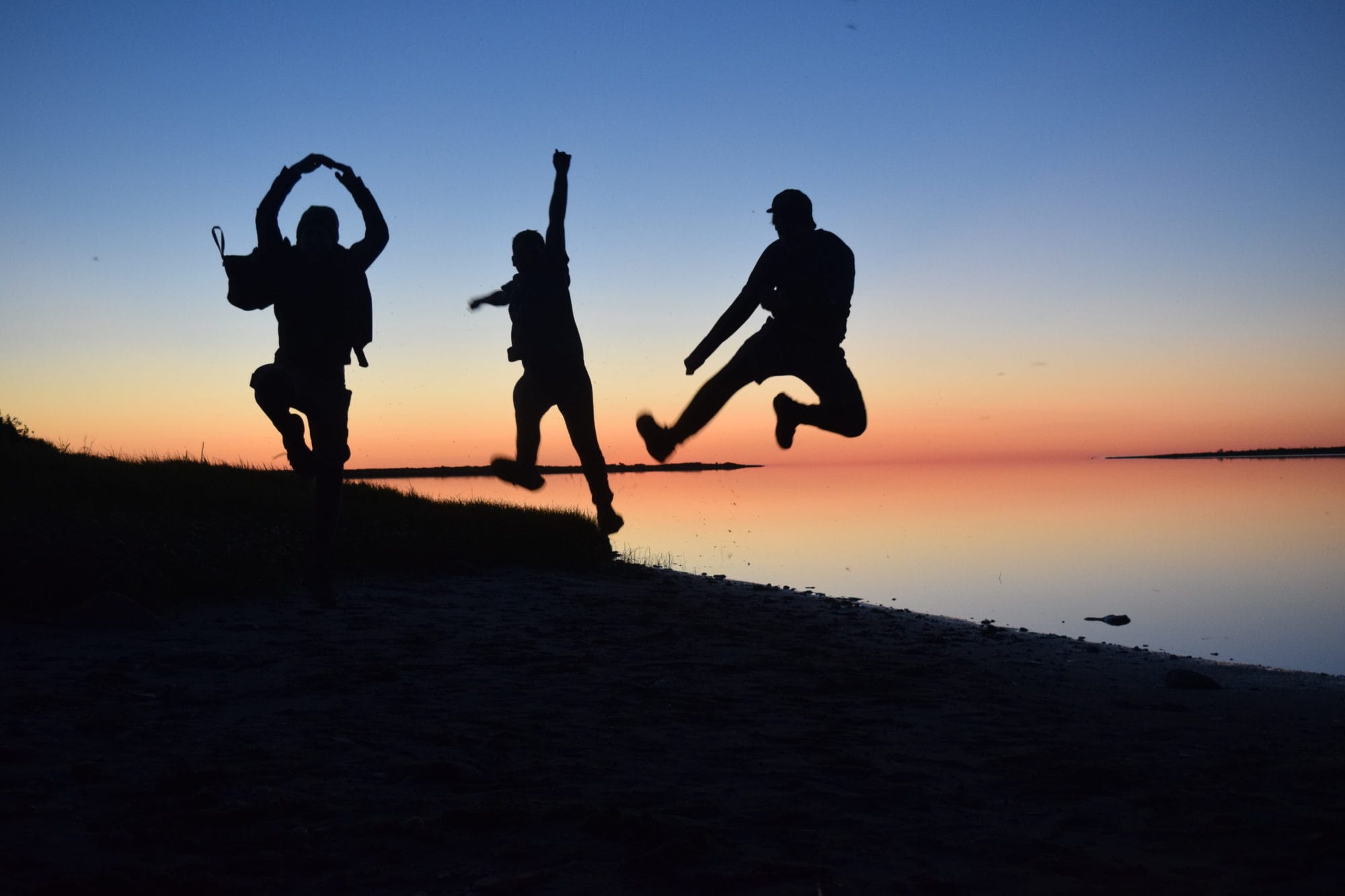 young men leaping into air silhouetted against sunset
