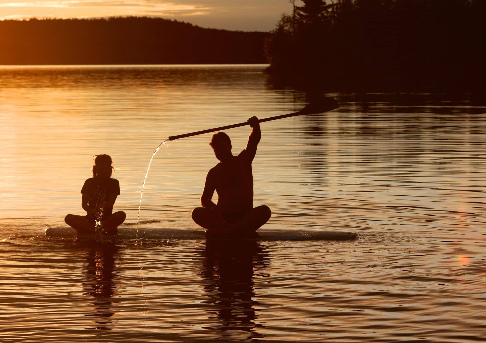 raising paddle against sunset sky